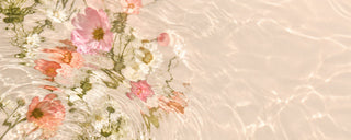 Soft pink and coral flowers reflected in rippling water